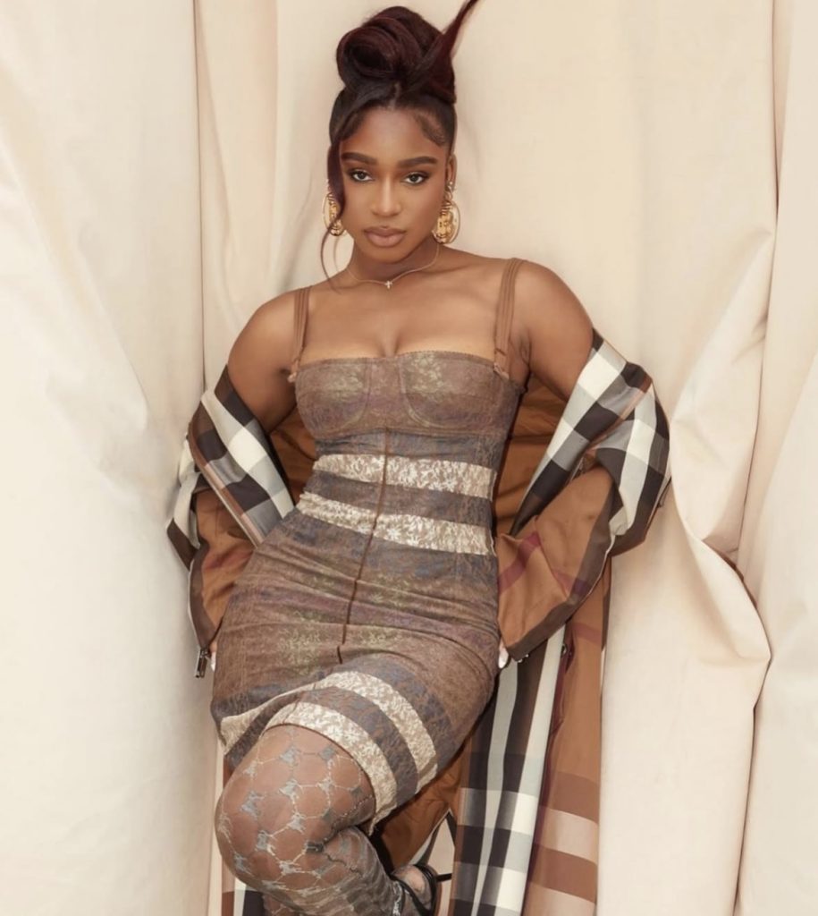 A beautiful black lady wearing an outfit from a fashion brand called Burberry
