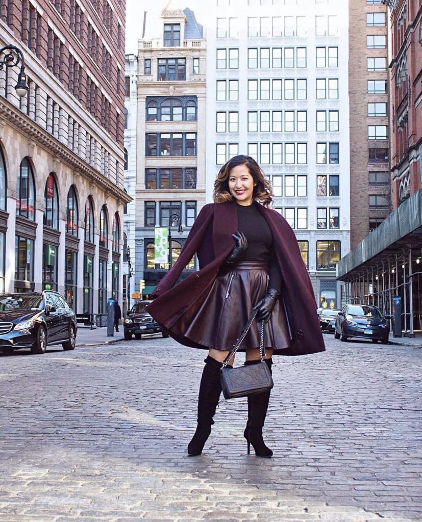A beautiful white lady wearing a maroon colored statement coat