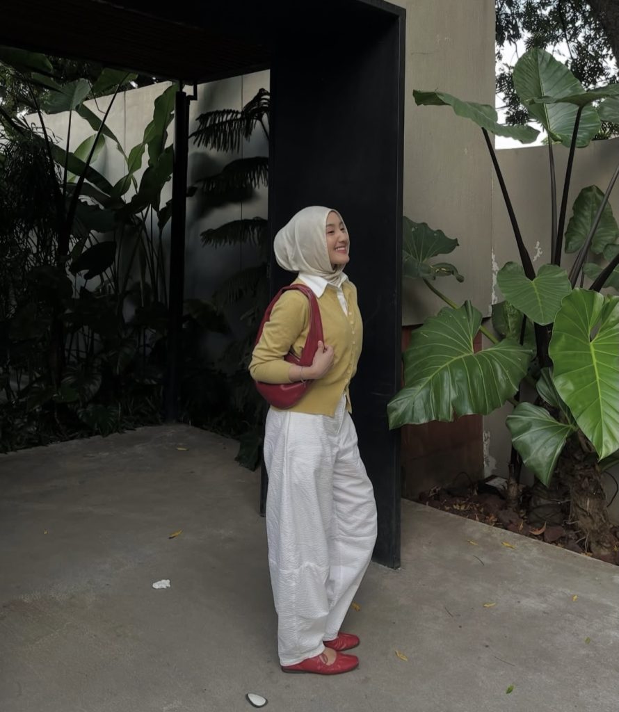 A lady dressed very modest in matching shoes and handbag