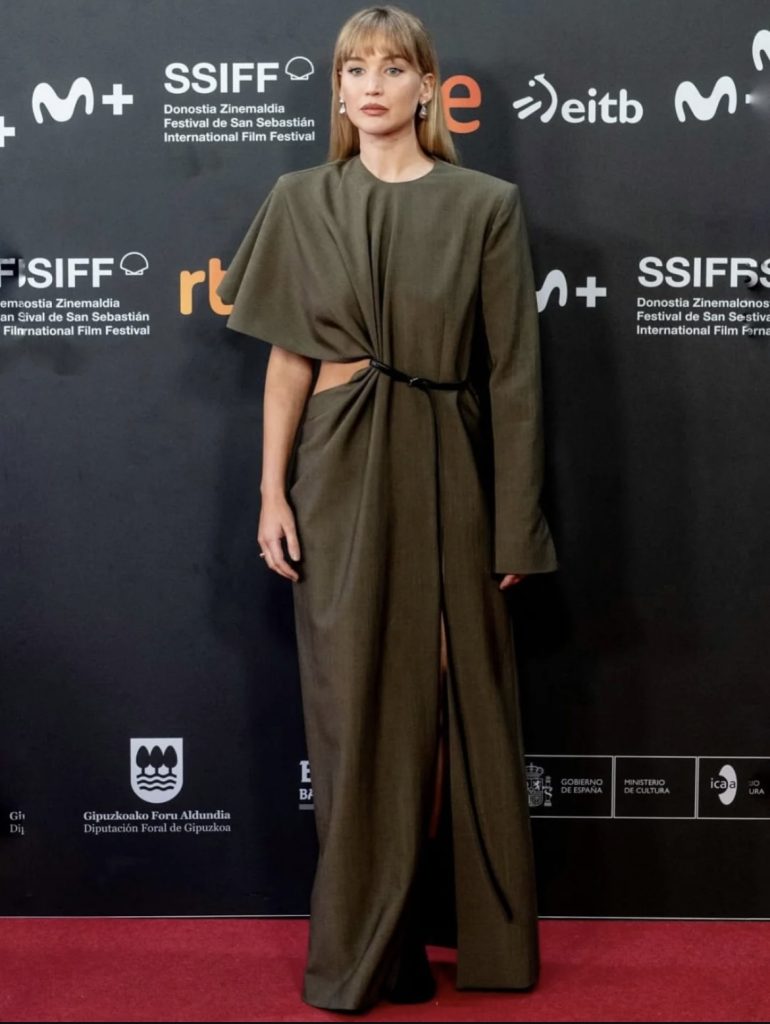 Jennifer Lawrence posing on a red carpet wearing a deep green cut out dress