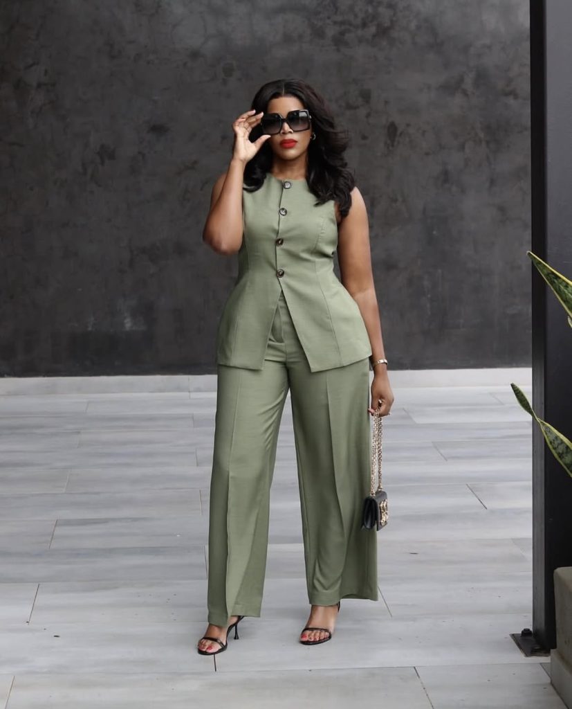 A beautiful lady wearing a two piece green tone of waist coat and skirt.