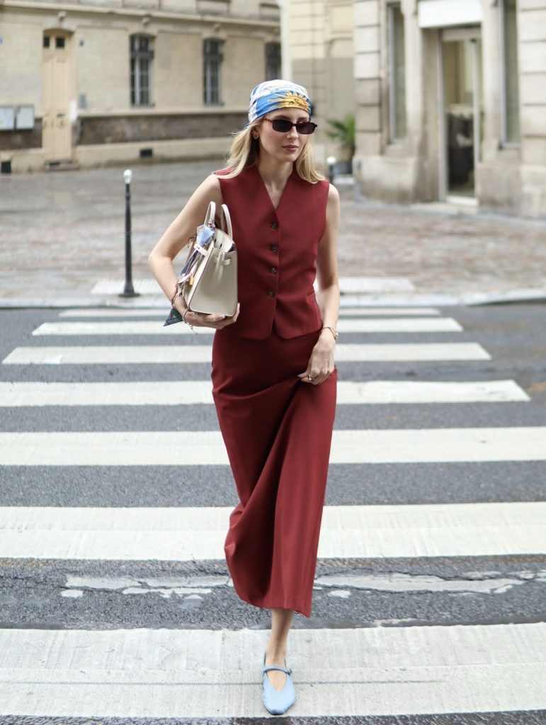 A beautiful lady wearing a two piece burgundy tone of waist coat and skirt.