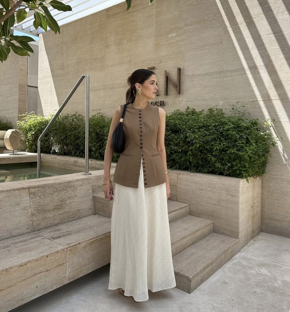 A beautiful lady wearing a neutral beige tone of waist coat and skirt.